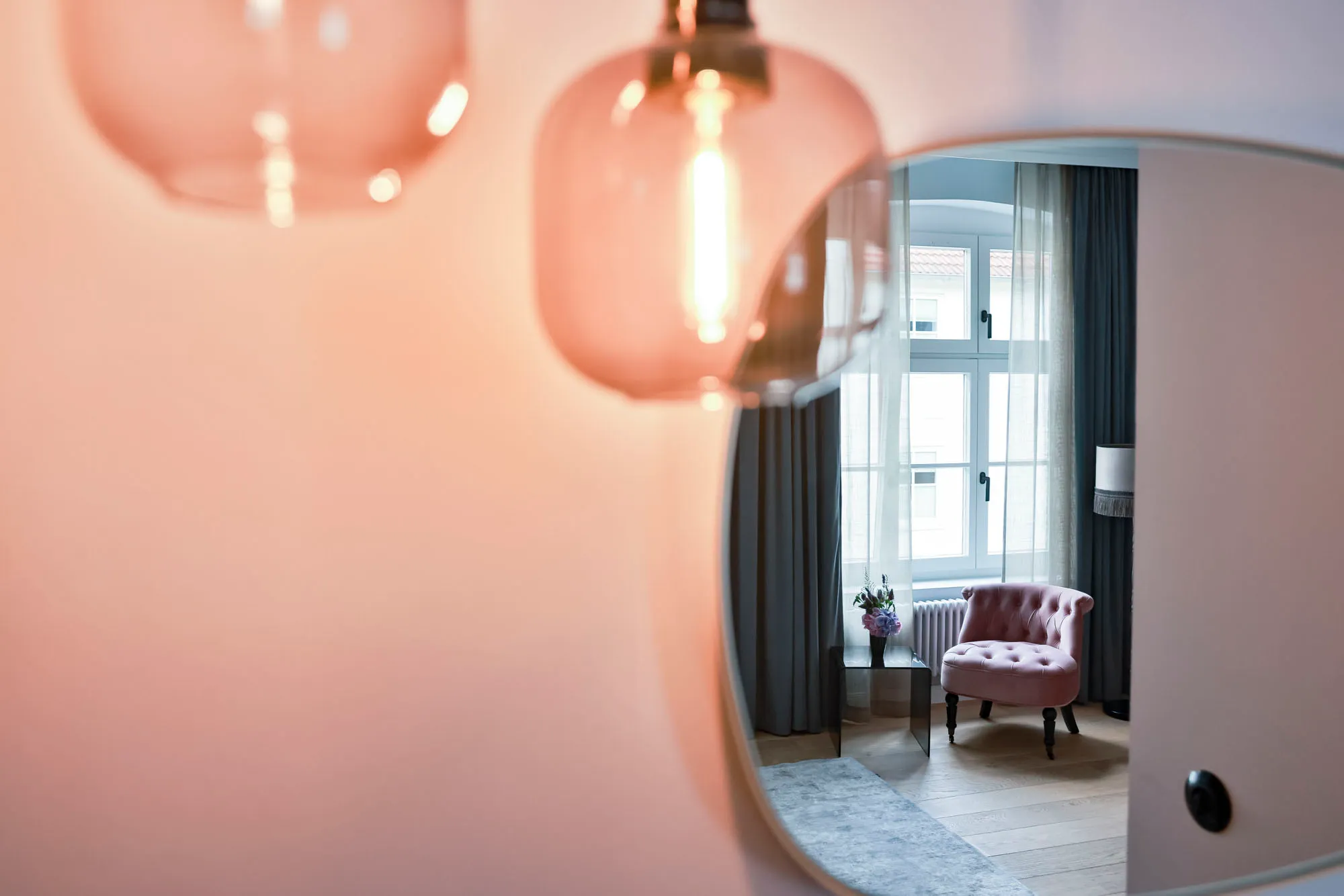 Badezimmer mit rundem Spiegel und Blick ins Zimmer