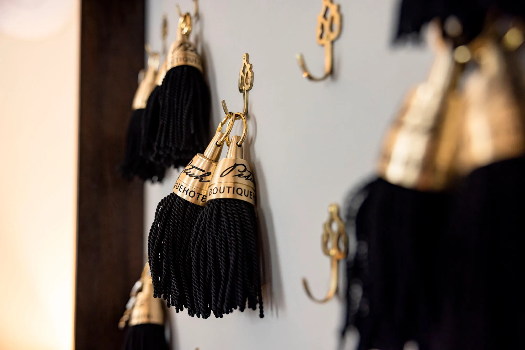 A Petuh room key with a black tassel and brass cap hanging on a hook