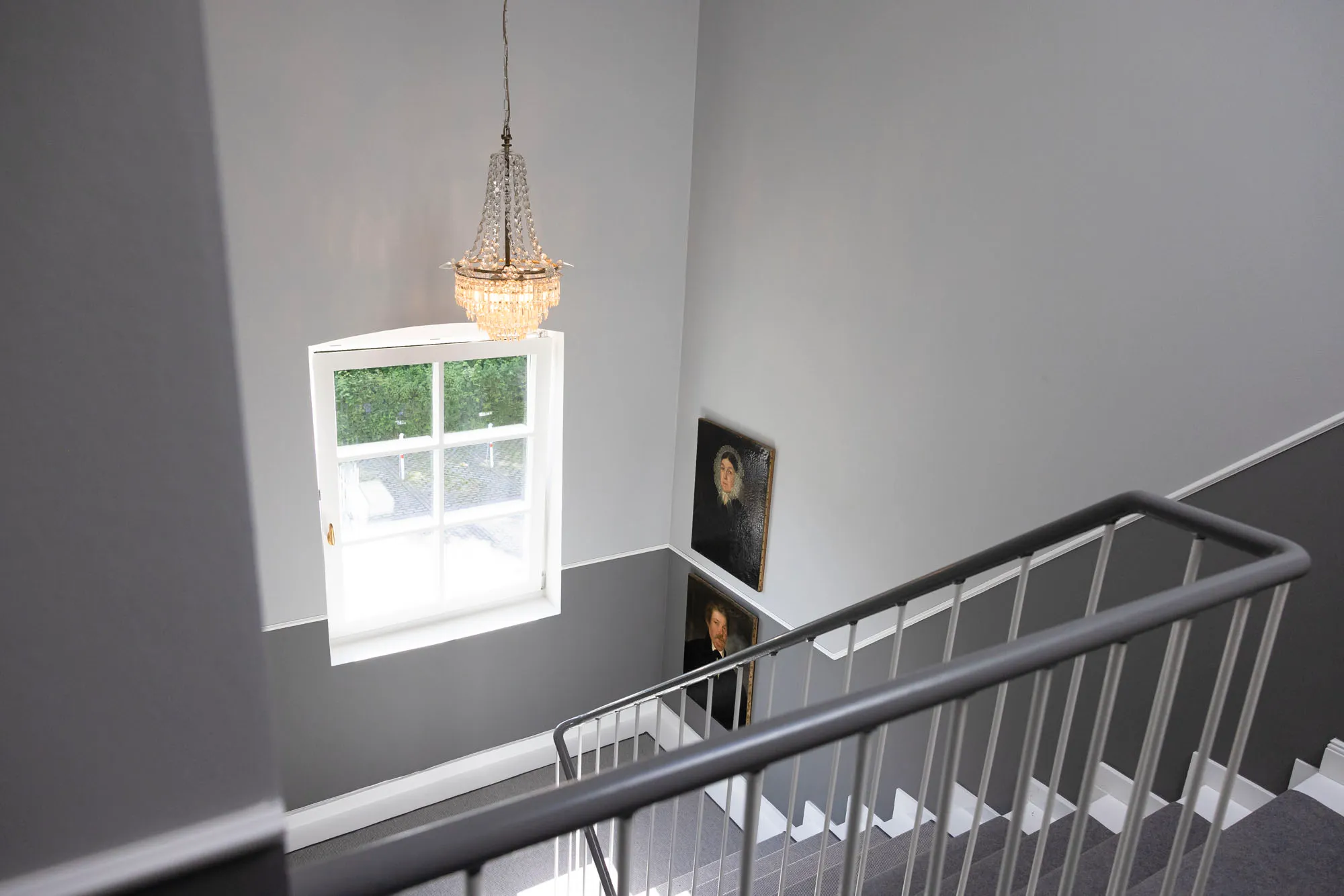 The staircase at Petuh with chandelier, sash window and historic portraits