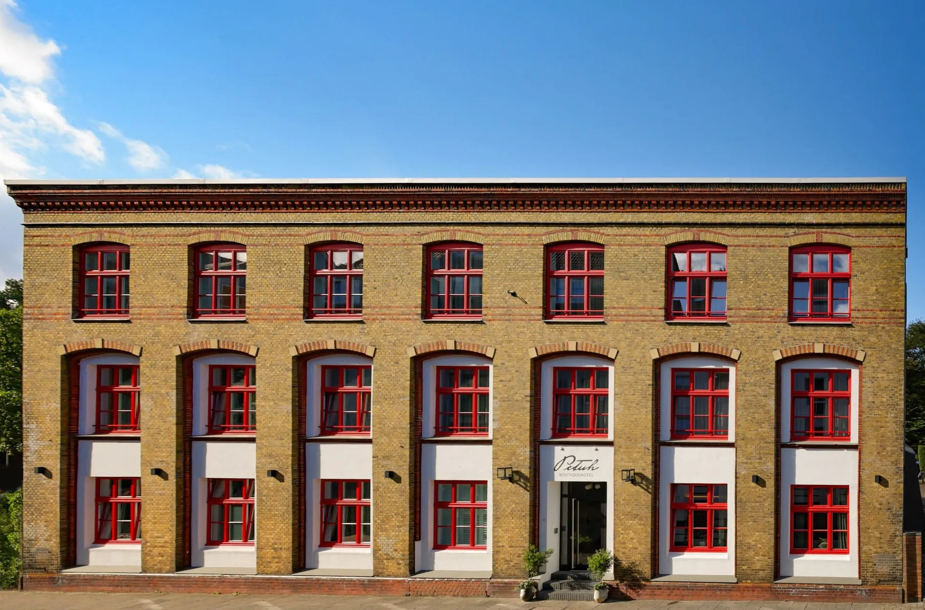 Brick façade of Boutiquehotel Petuh with red sash windows