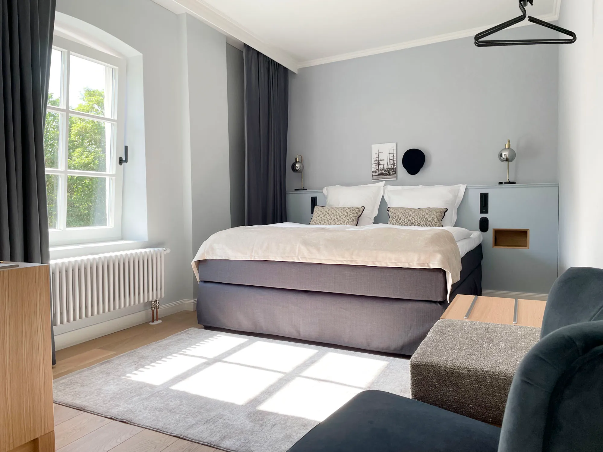 Zimmer Le Classique im Petuh mit gemachtem Bett, Messingleuchten und Blumen im Vordergrund