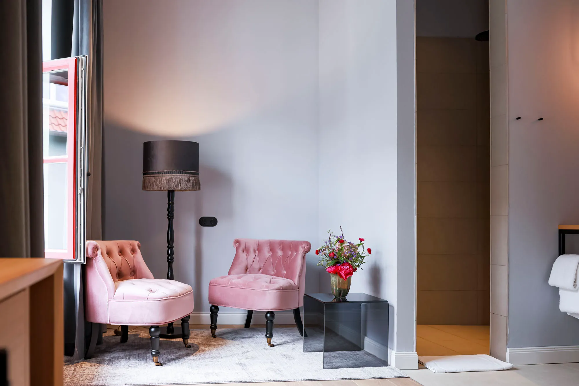 Two rose velvet armchairs by the window with a bunch of flowers